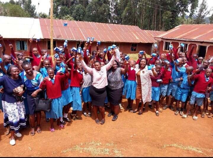 Schoolgirls and JOFA staff celebrating a dignity-kit distribution outside their school